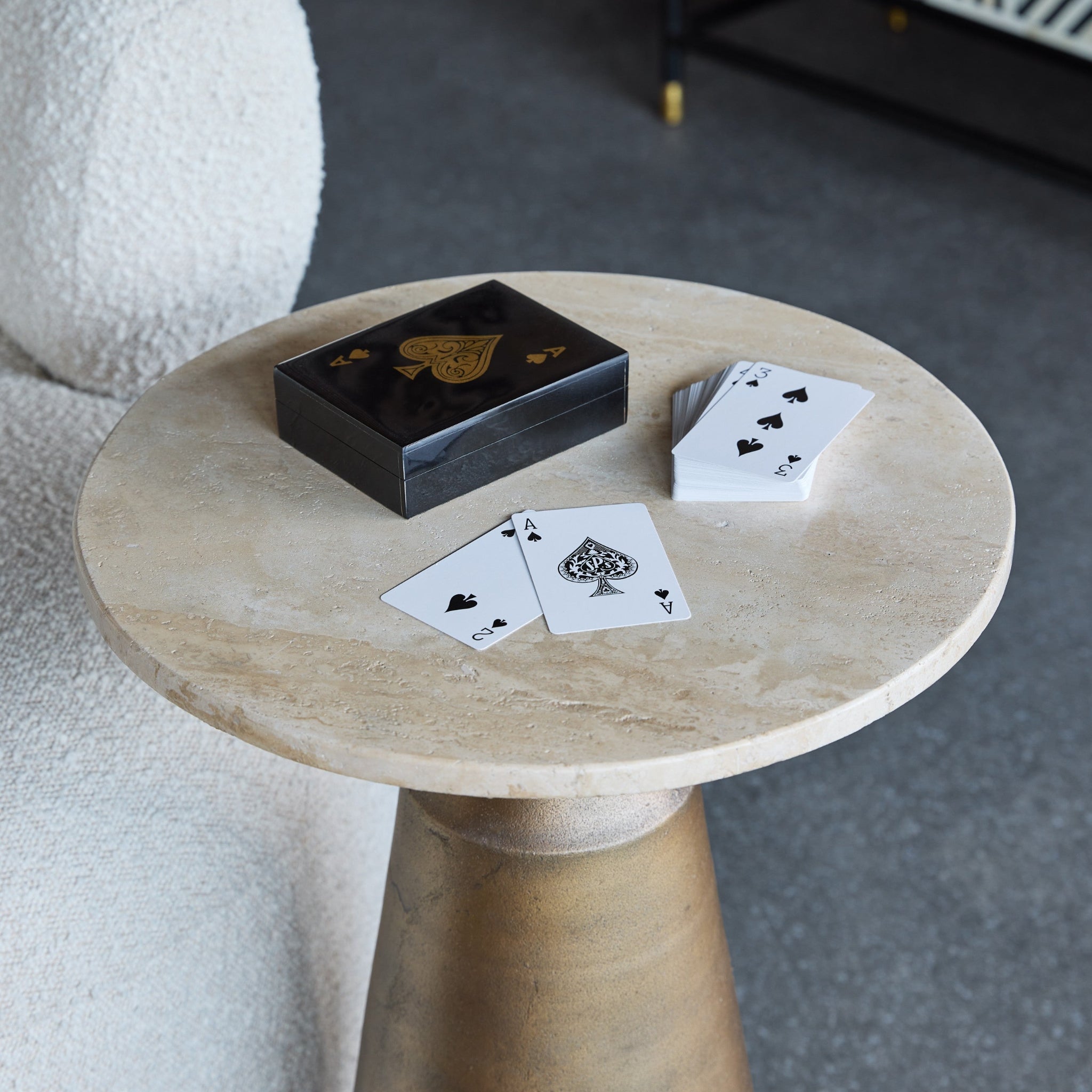 Wooden side table with playing cards and a deck on a carpeted floor.