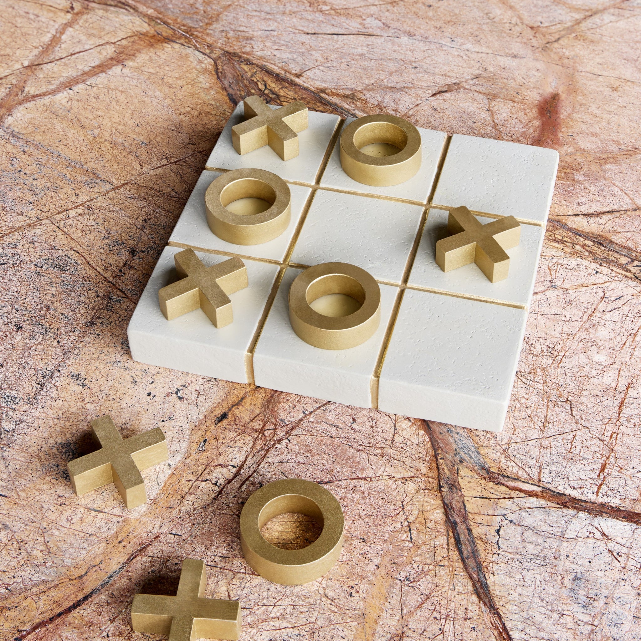 Tic-tac-toe game set on a marble surface with wooden pieces.