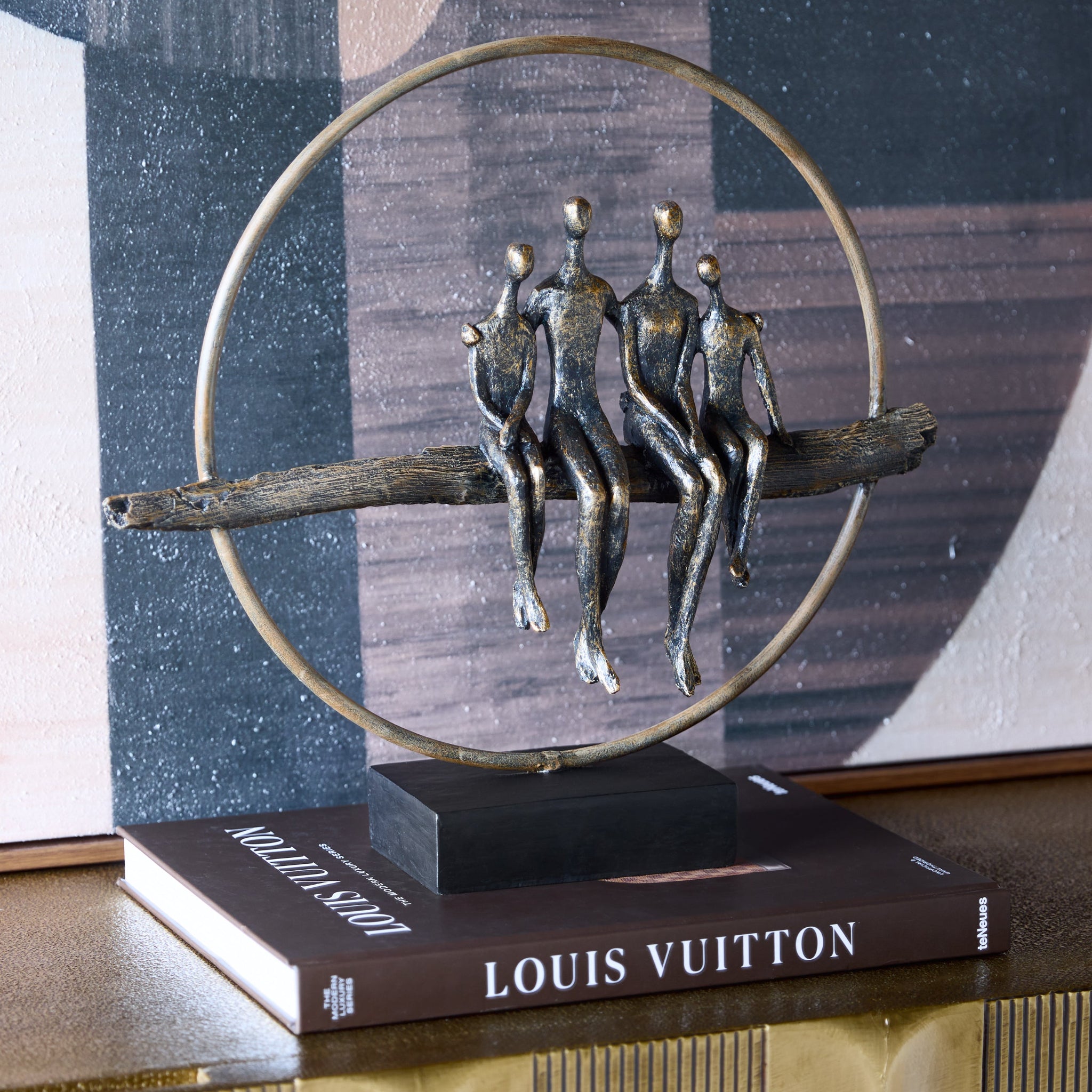 Decorative sculpture of people on a branch with a Louis Vuitton book underneath