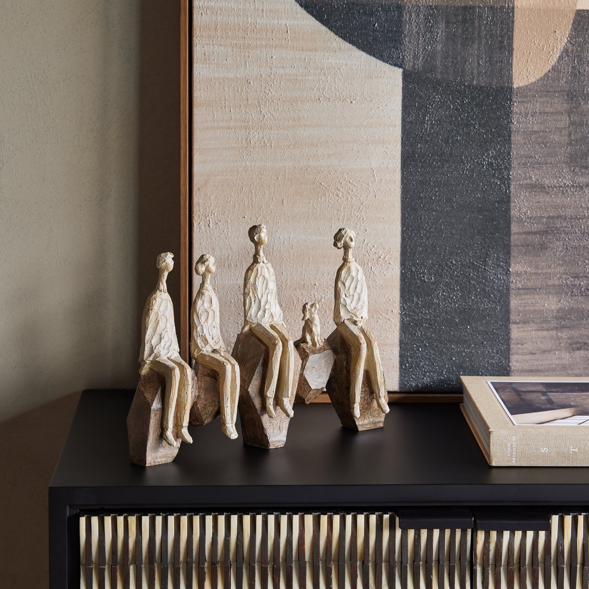 Decorative sculptures on a black surface with abstract art in the background