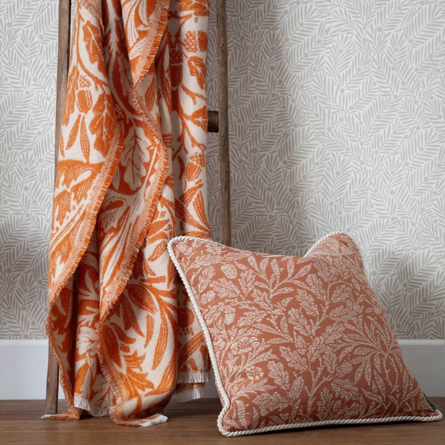 Patterned orange and white blanket and pillow against a textured wall.