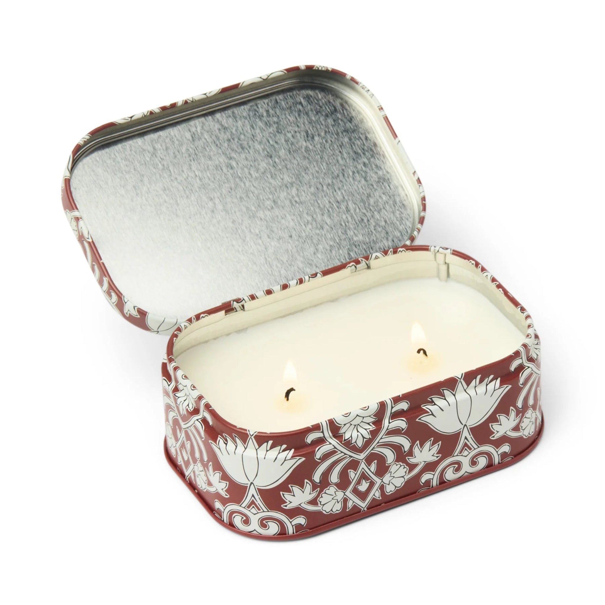 Candle in a decorative tin with floral patterns on a white background