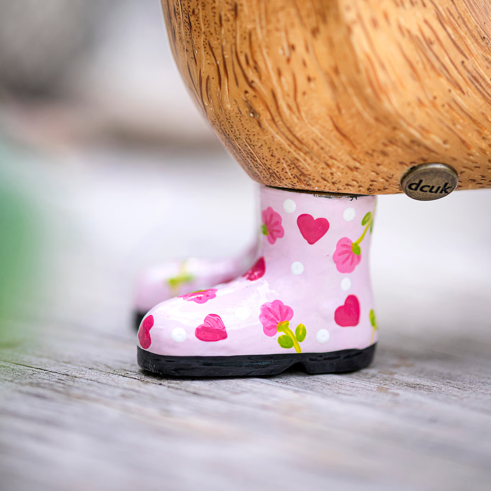 Pink rain boot with heart and flower pattern on a wooden duck