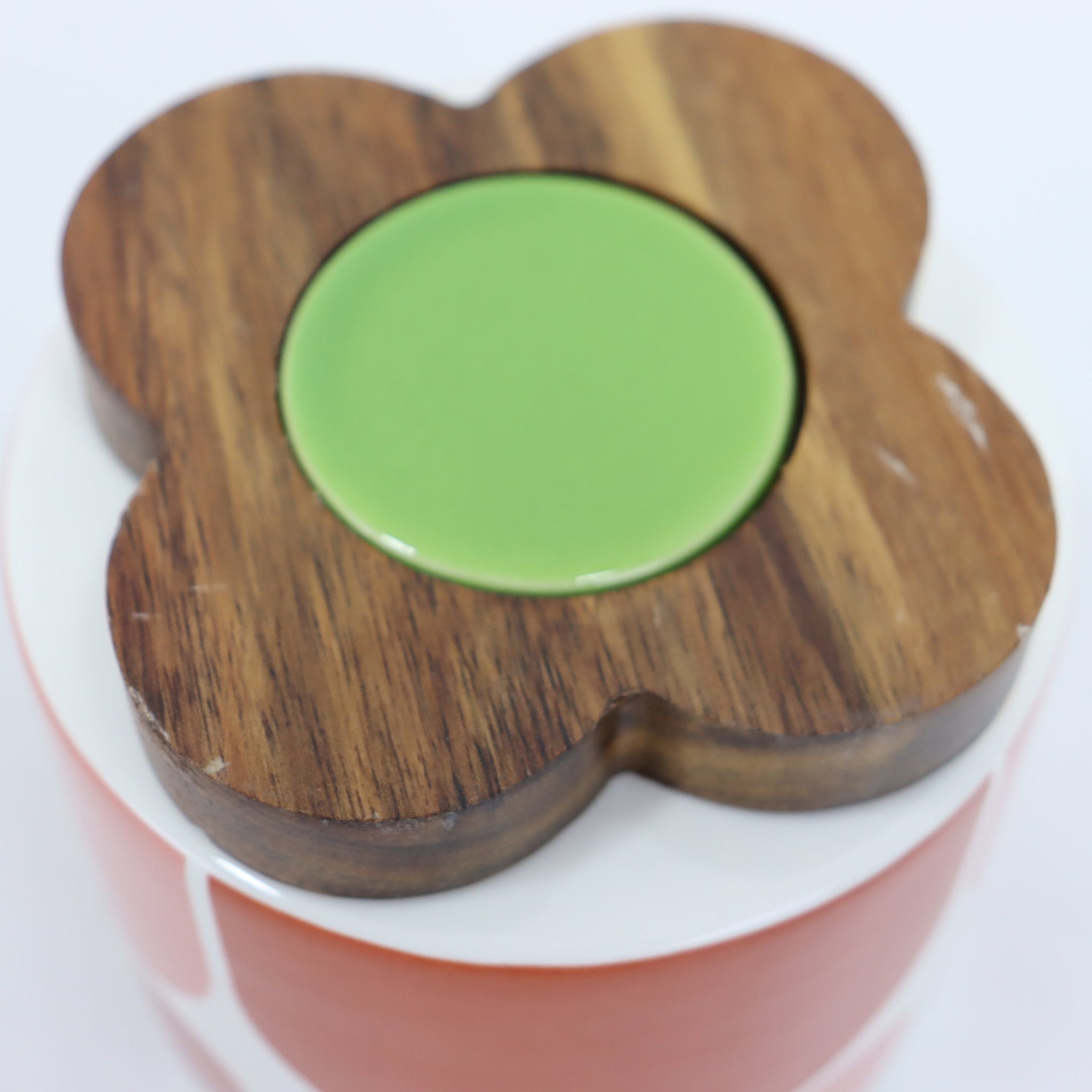 Wooden flower-shaped container with a green lid on a white background