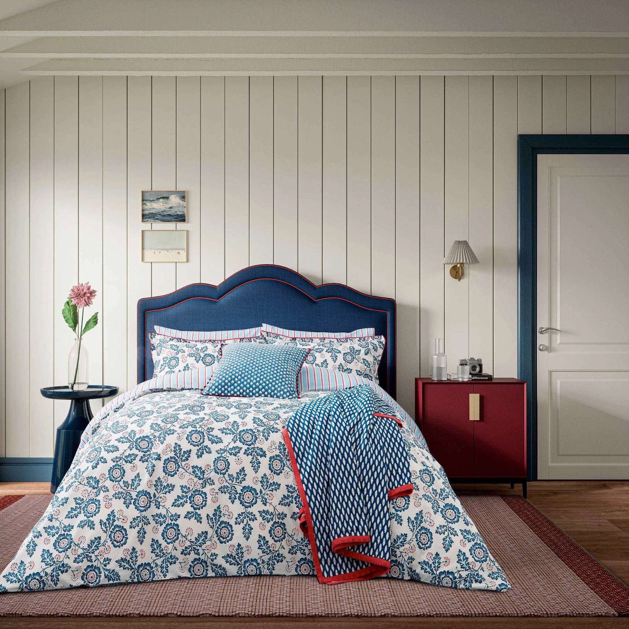 Bedroom with floral bedding, blue headboard, and red nightstand.