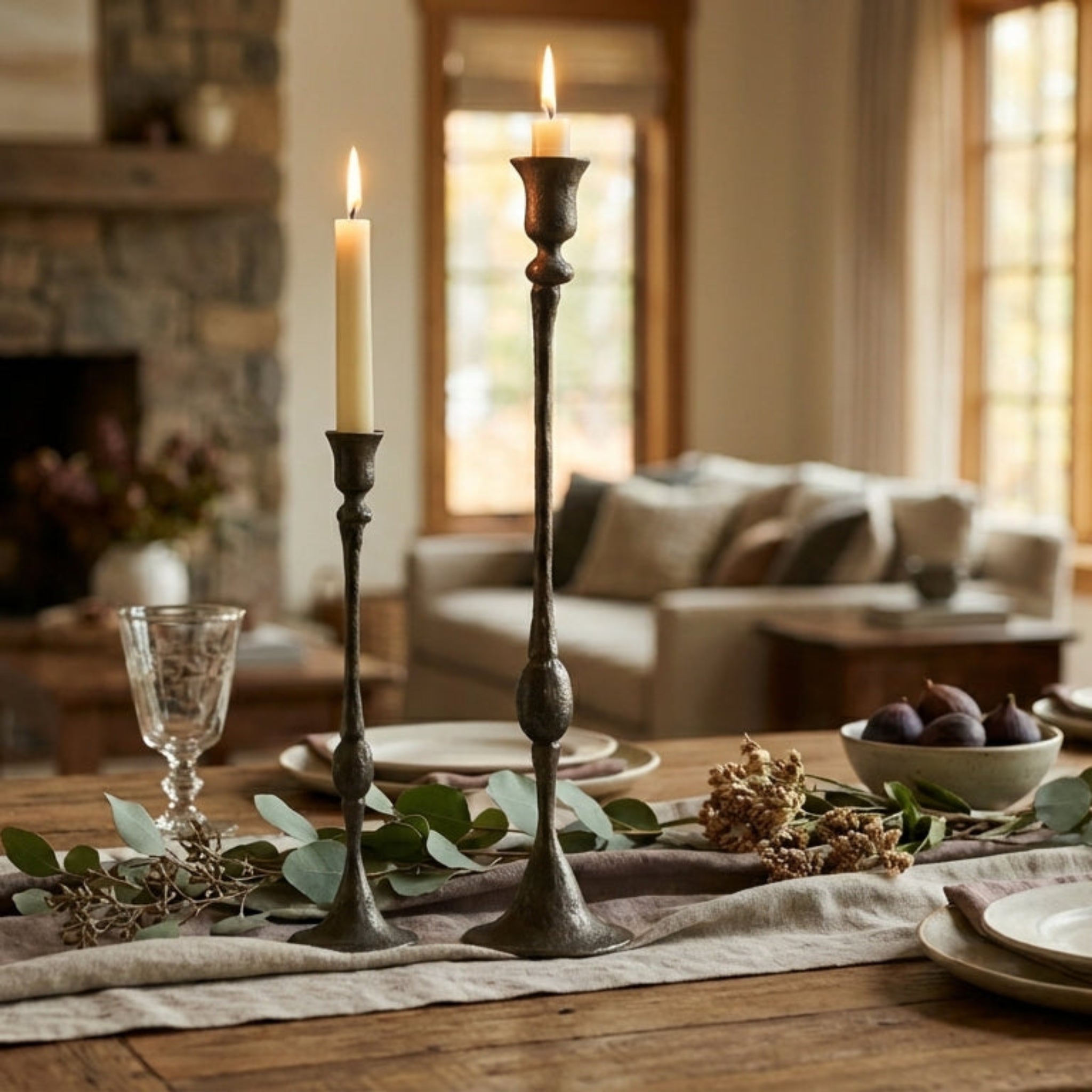 Dining table set with candles, glasses, and plates in a cozy living room.