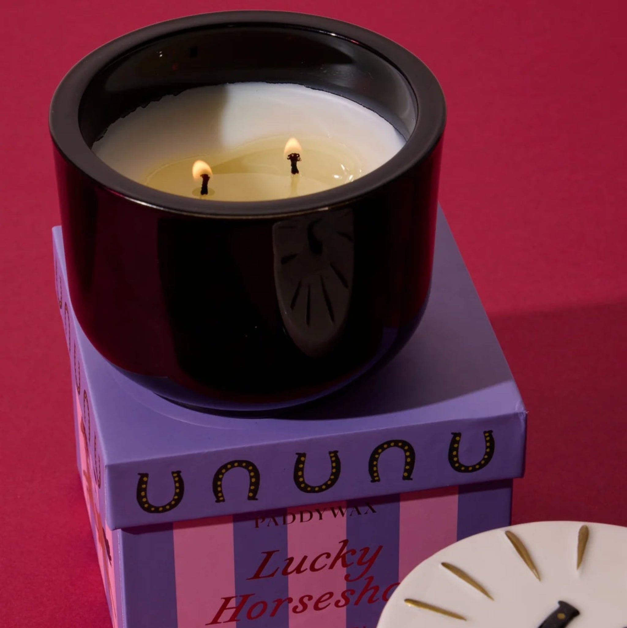 Candle in a black holder with a purple box labeled &