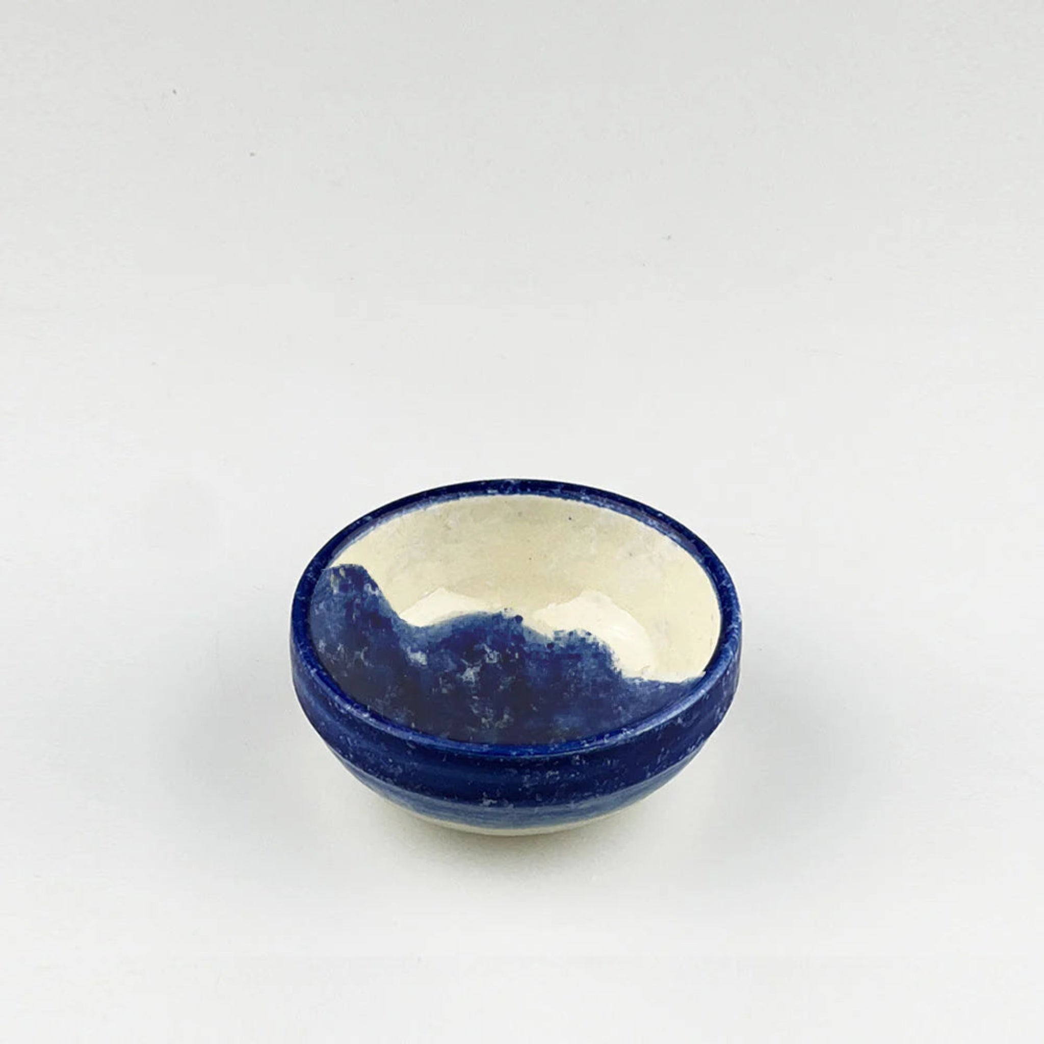 Ceramic bowl with blue exterior and white interior on a light gray background