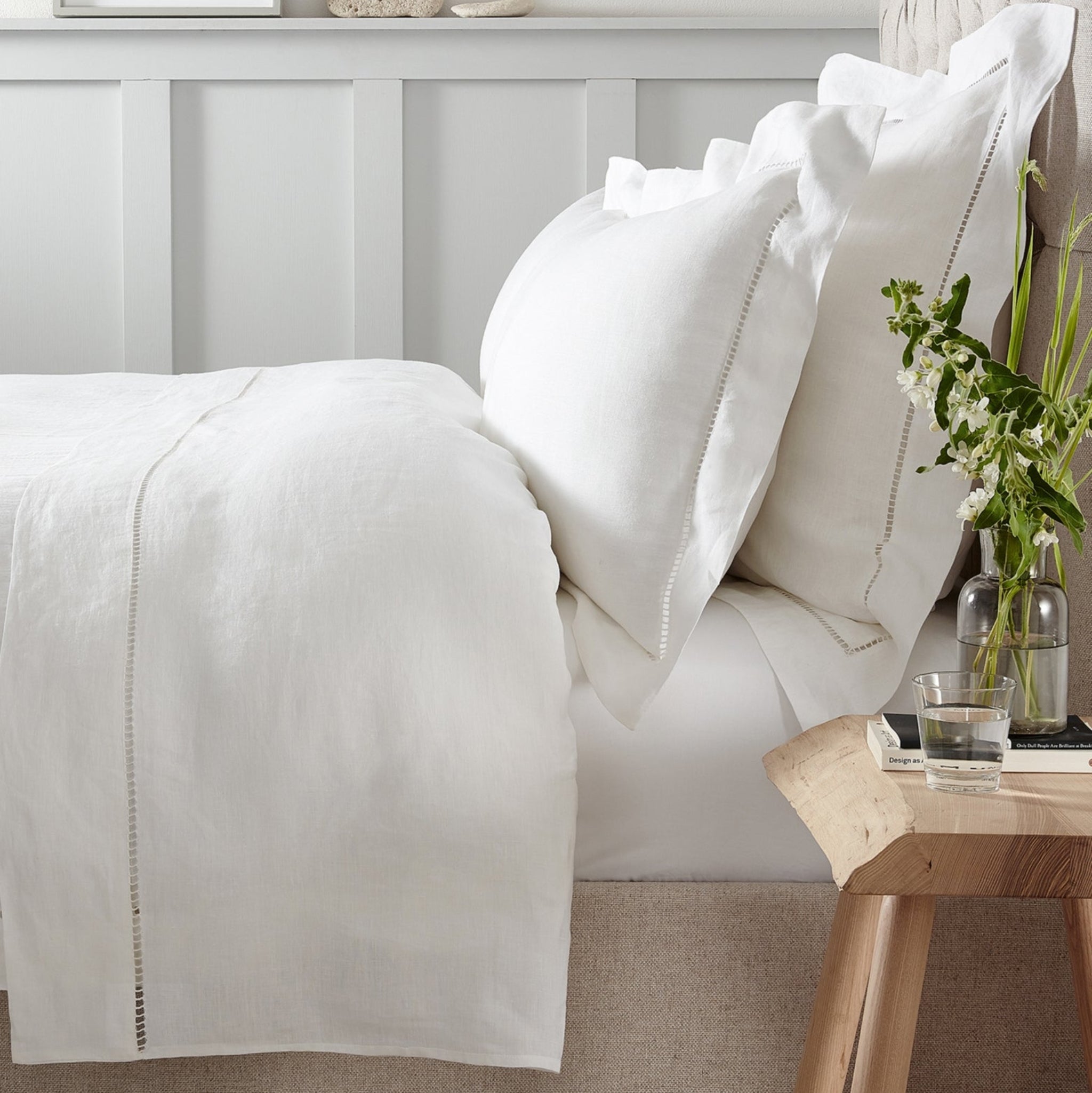 Neatly made bed with white bedding in a bedroom setting.
