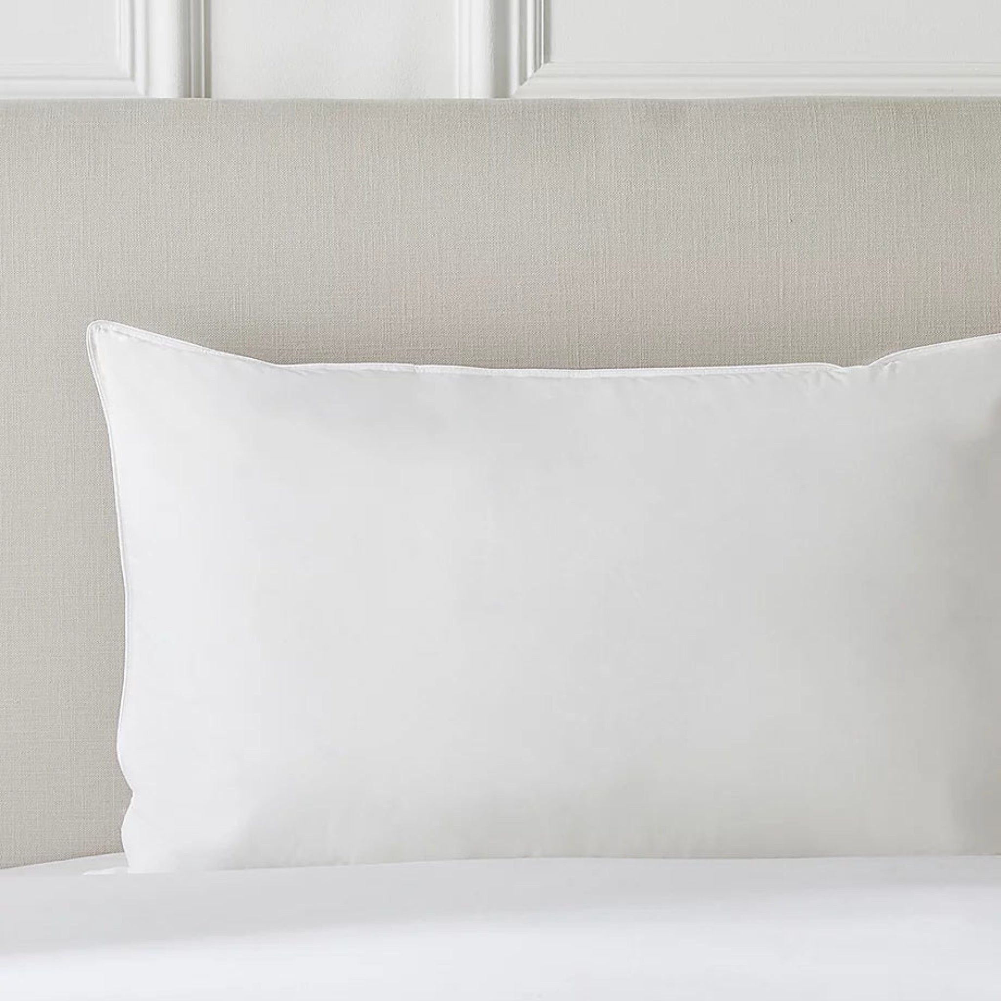White pillow on a bed with a neutral headboard
