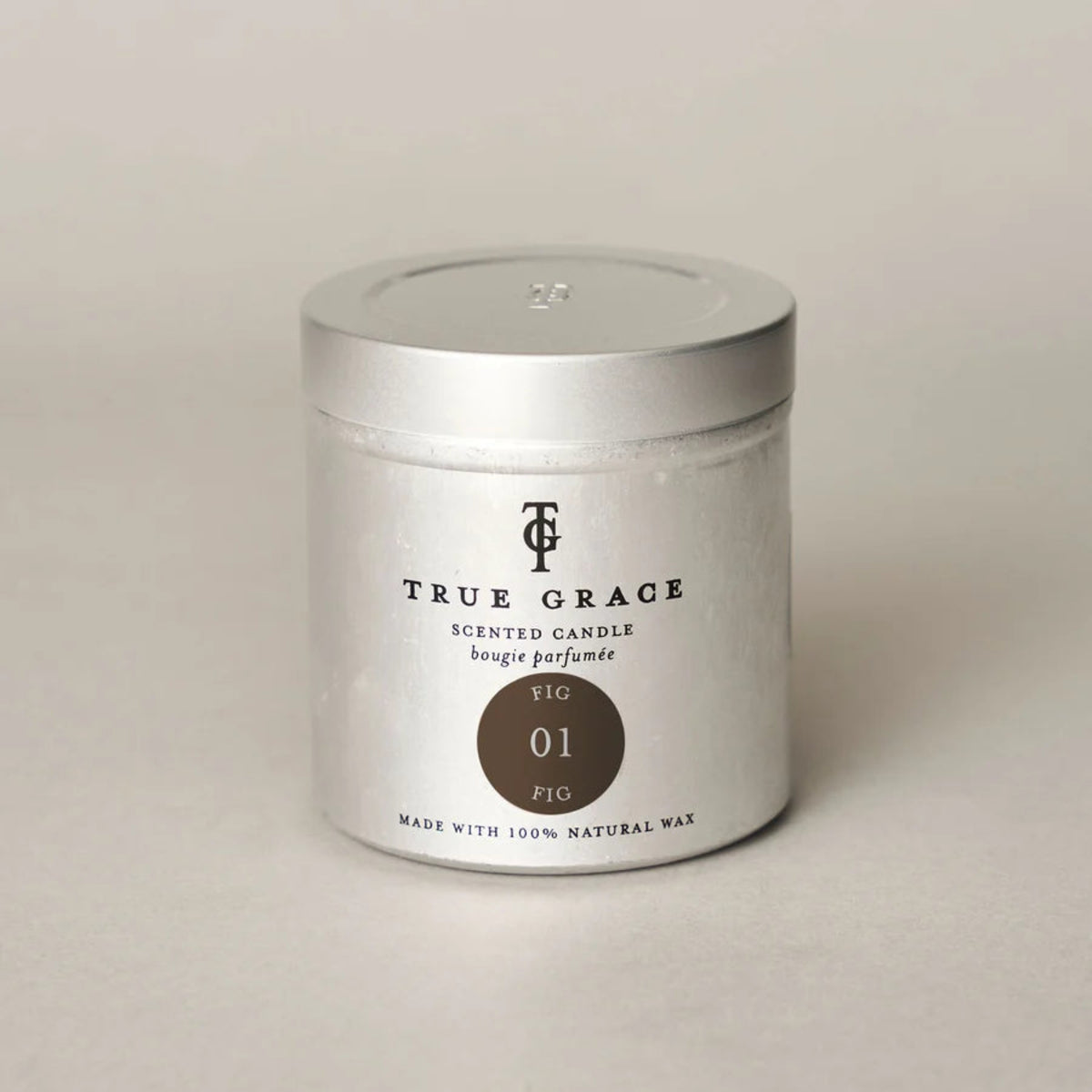 A silver metal tin candle from the brand True Grace, labeled &