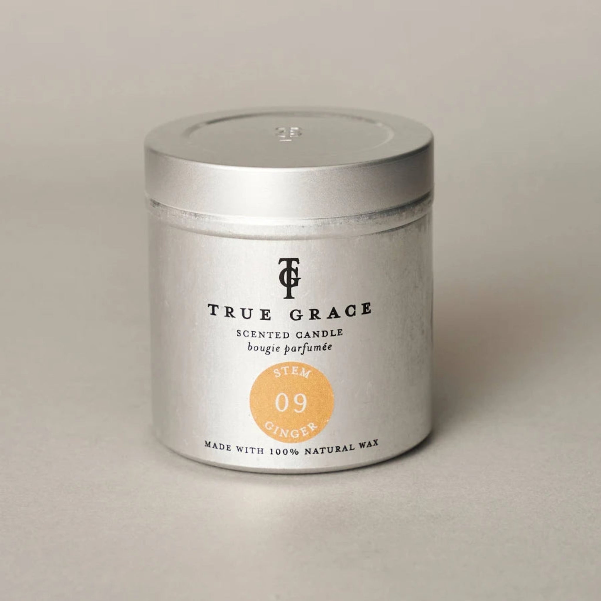 True Grace scented candle in a silver tin on a beige background