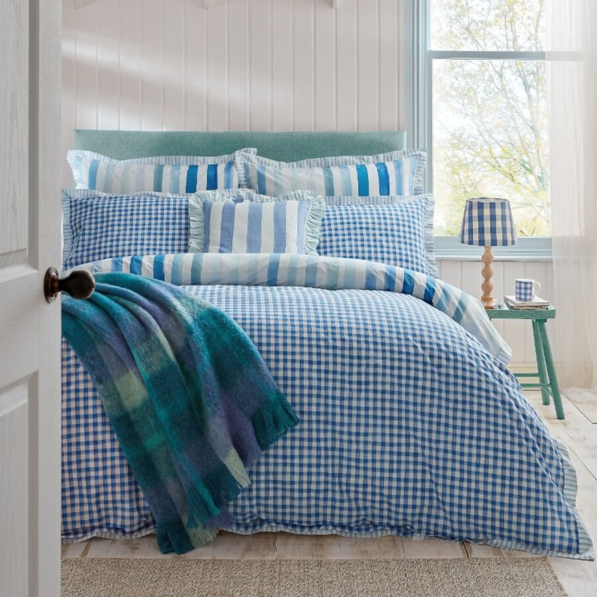 Bedroom with blue and white checkered bedding and striped pillows.