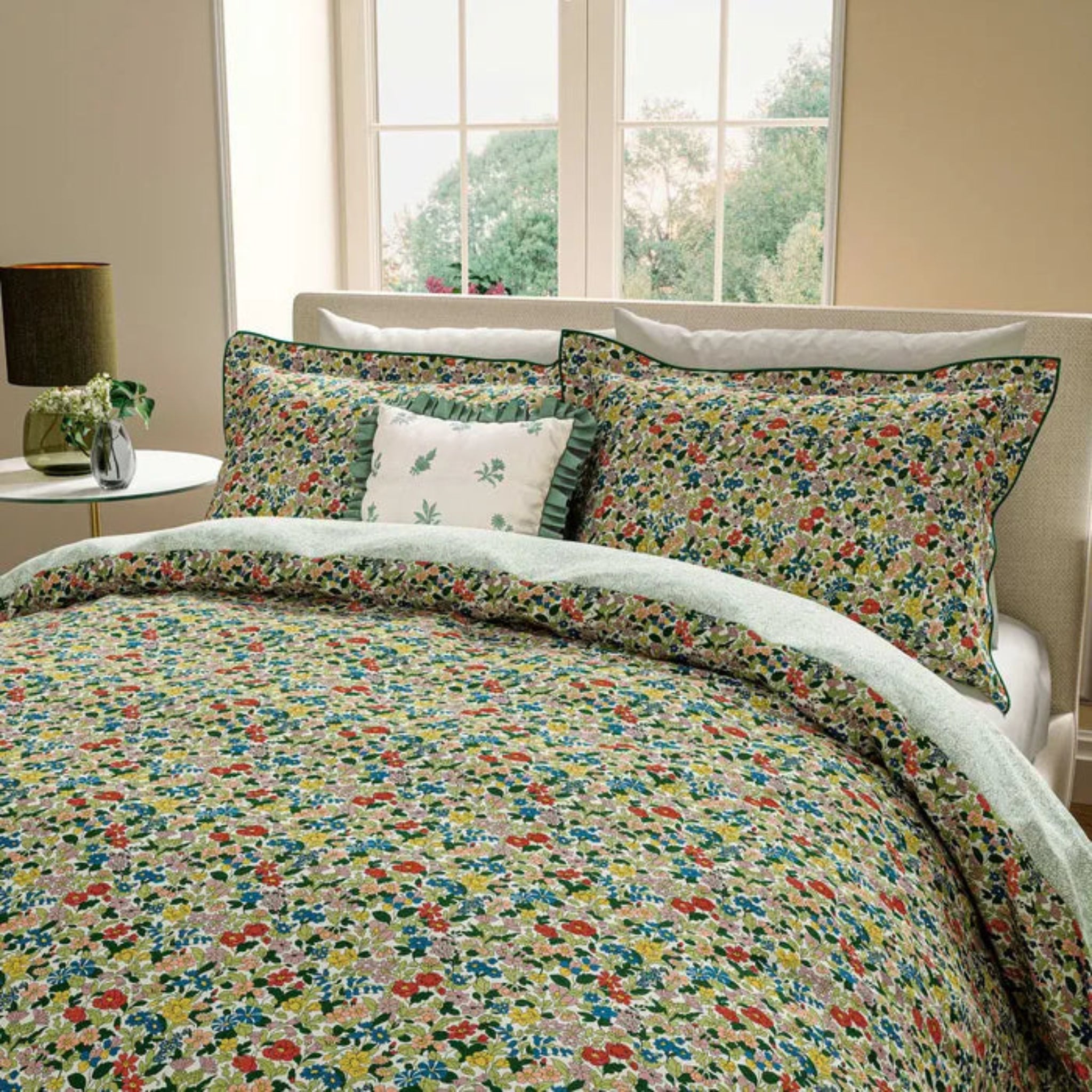 Floral bedding set on a bed with a lamp and window in the background
