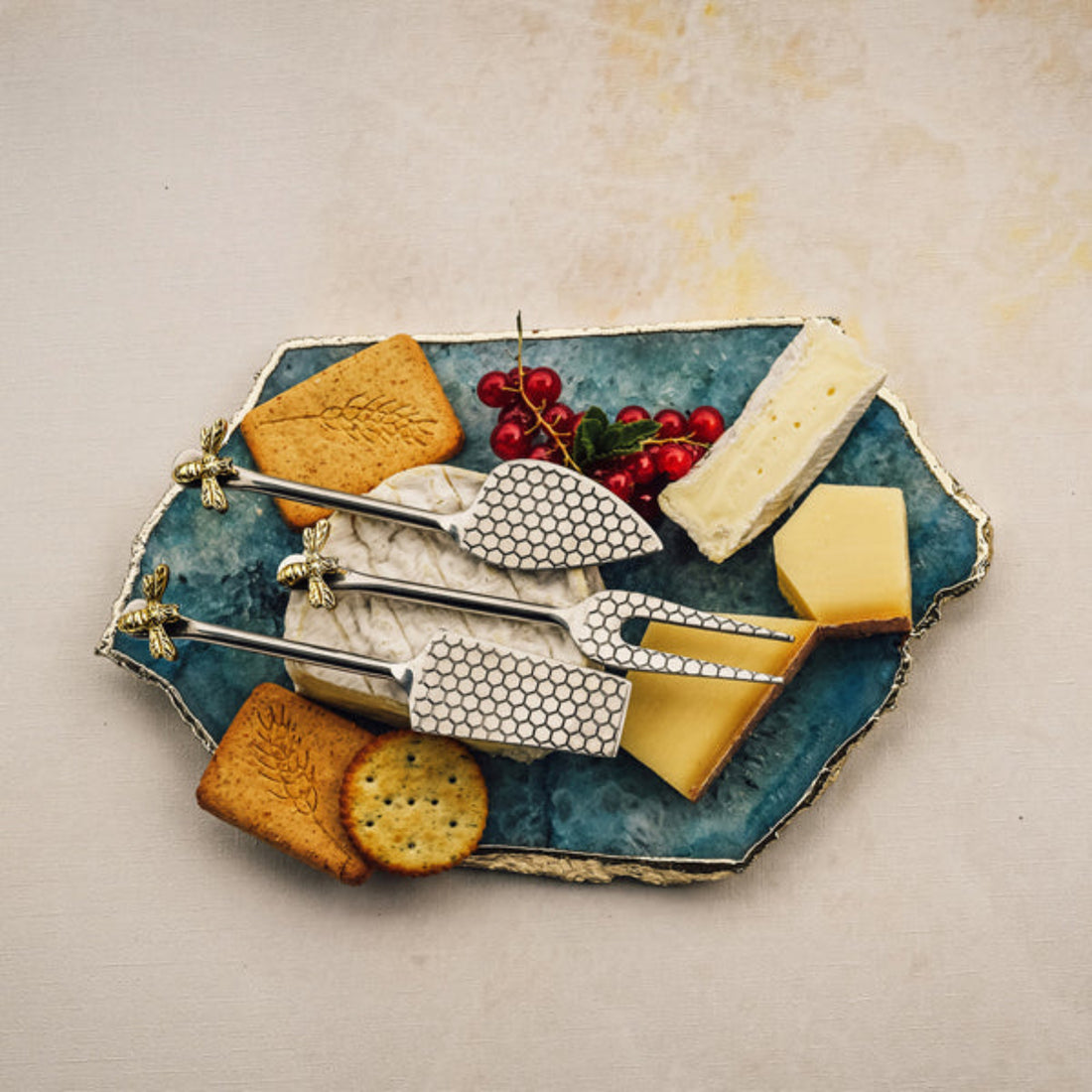 Cheese platter with cheese, crackers, and fruit on a textured surface