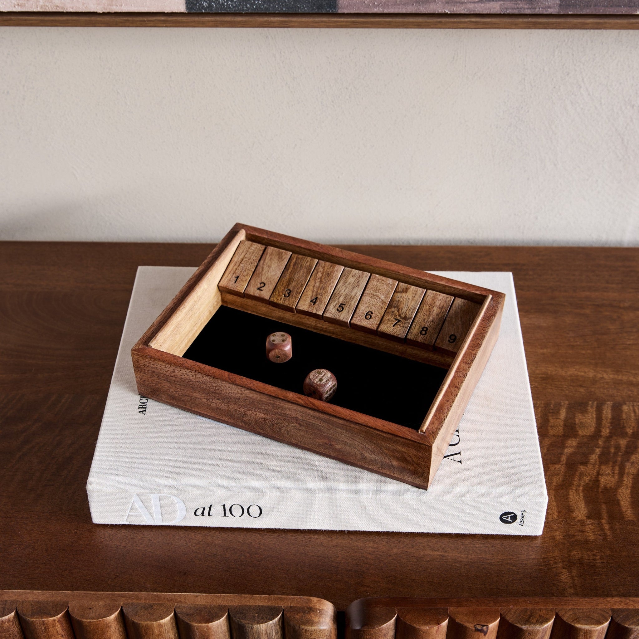 Wooden box with a lid on top of a book on a wooden surface