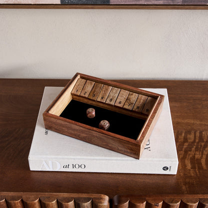 Wooden box with a lid on top of a book on a wooden surface