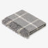 A folded gray plaid throw blanket with fringed edges, displayed on a clean white background.