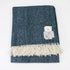 Blue herringbone patterned throw blanket with white fringe on a white background