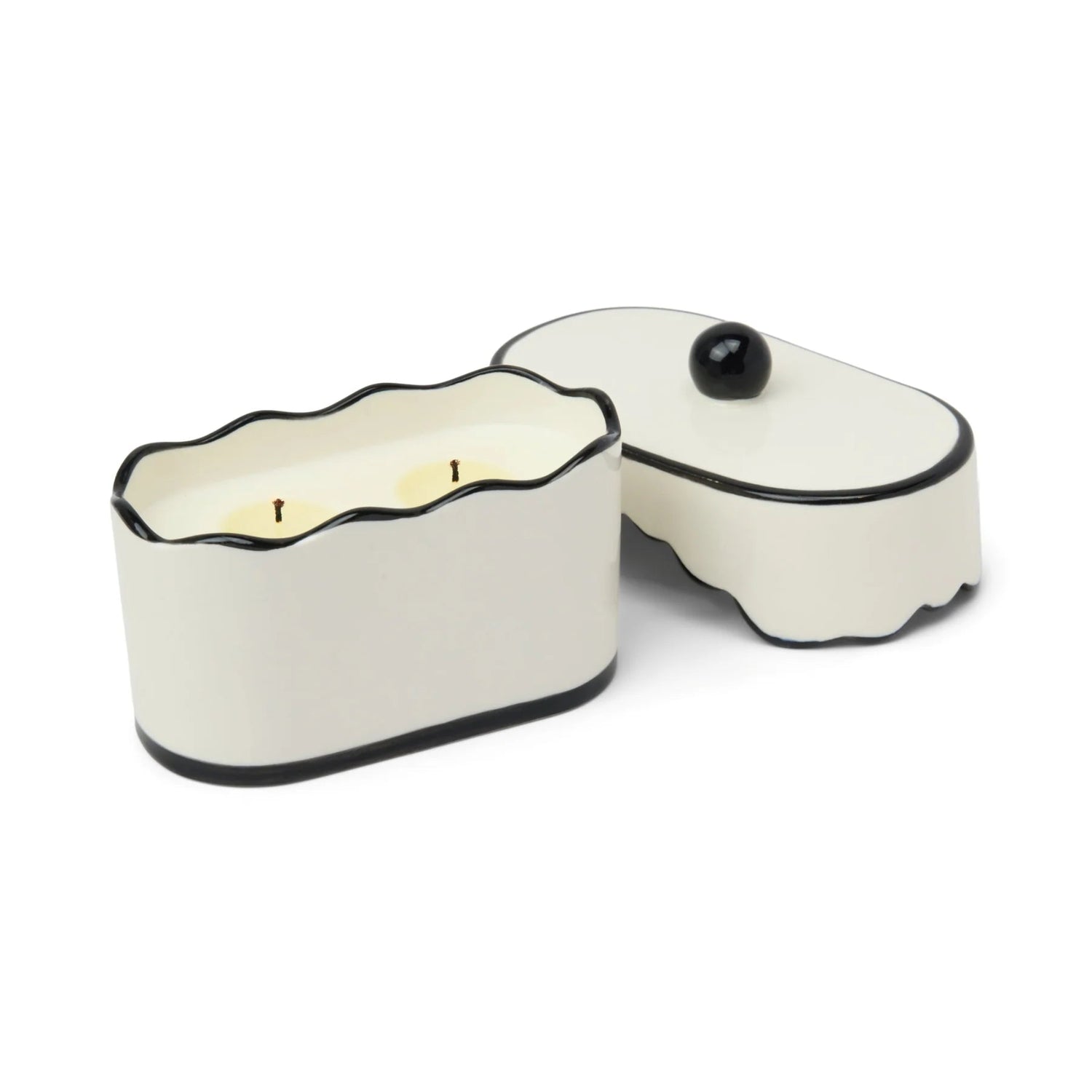 White ceramic container with black rim holding a lit candle on a white background