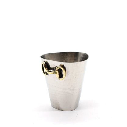 A small hammered silver metal cup with a gold horsebit handle, photographed on a clean white background.