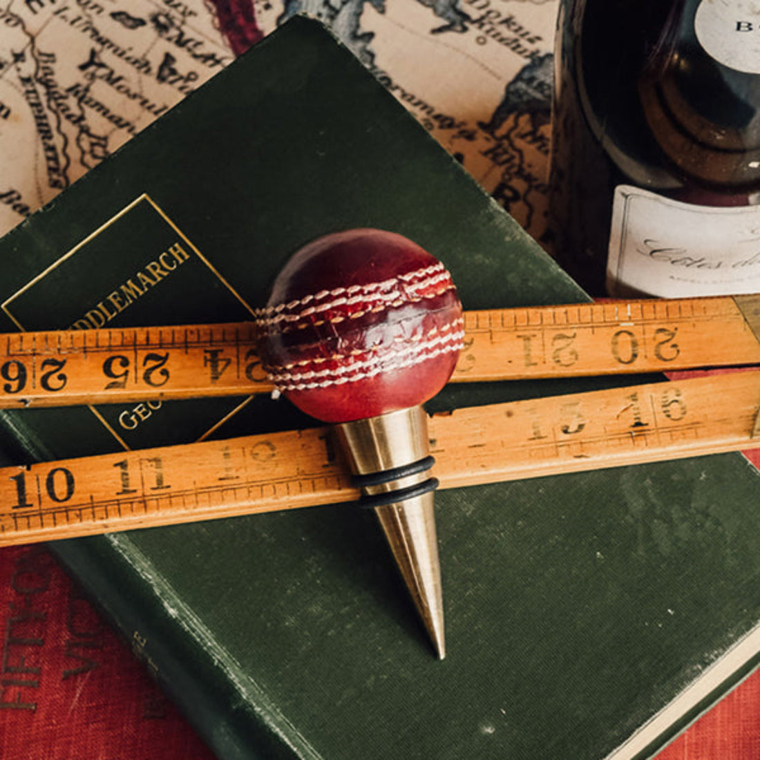 Cricket ball bottle stopper on a book with a ruler