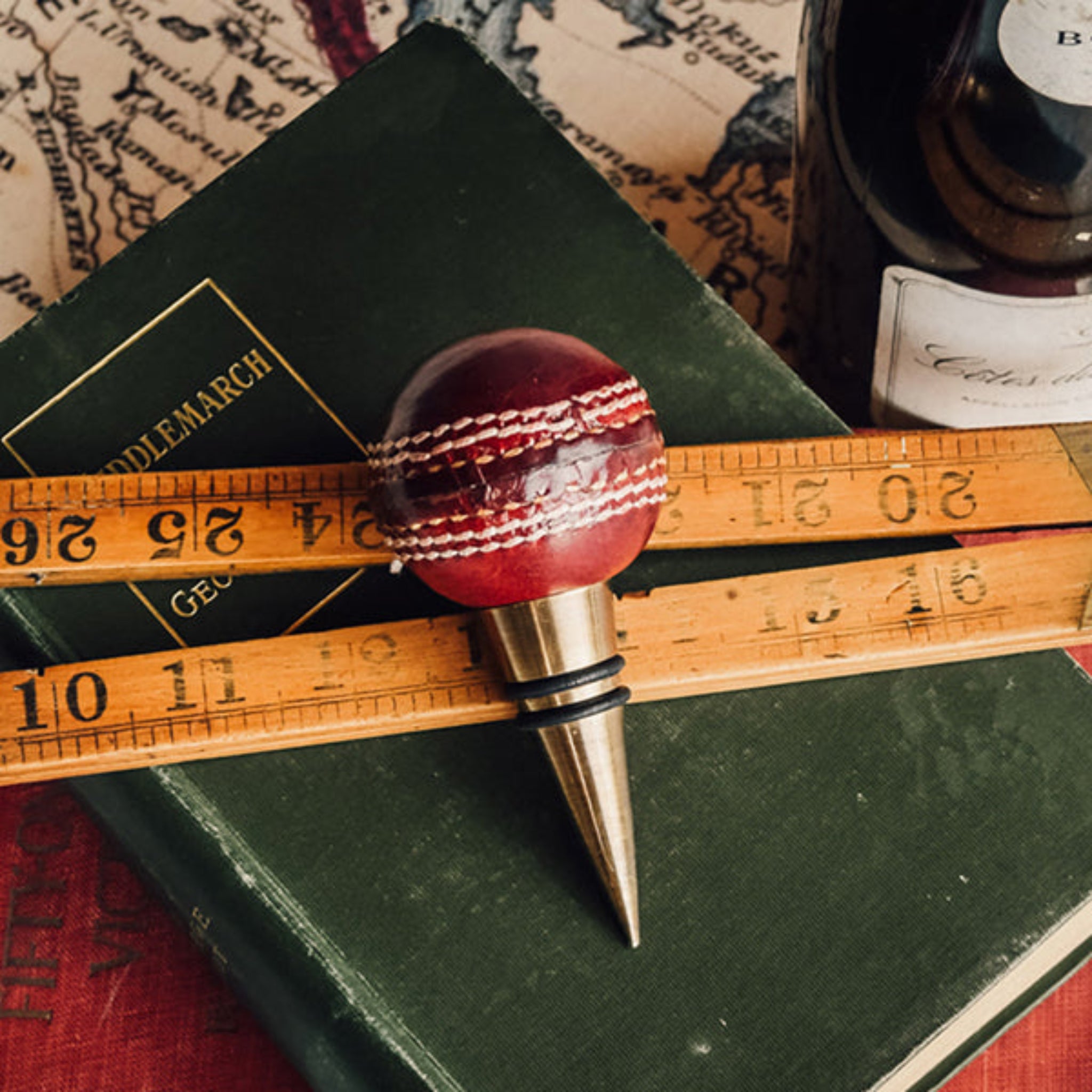 Cricket ball bottle stopper on a book with a ruler