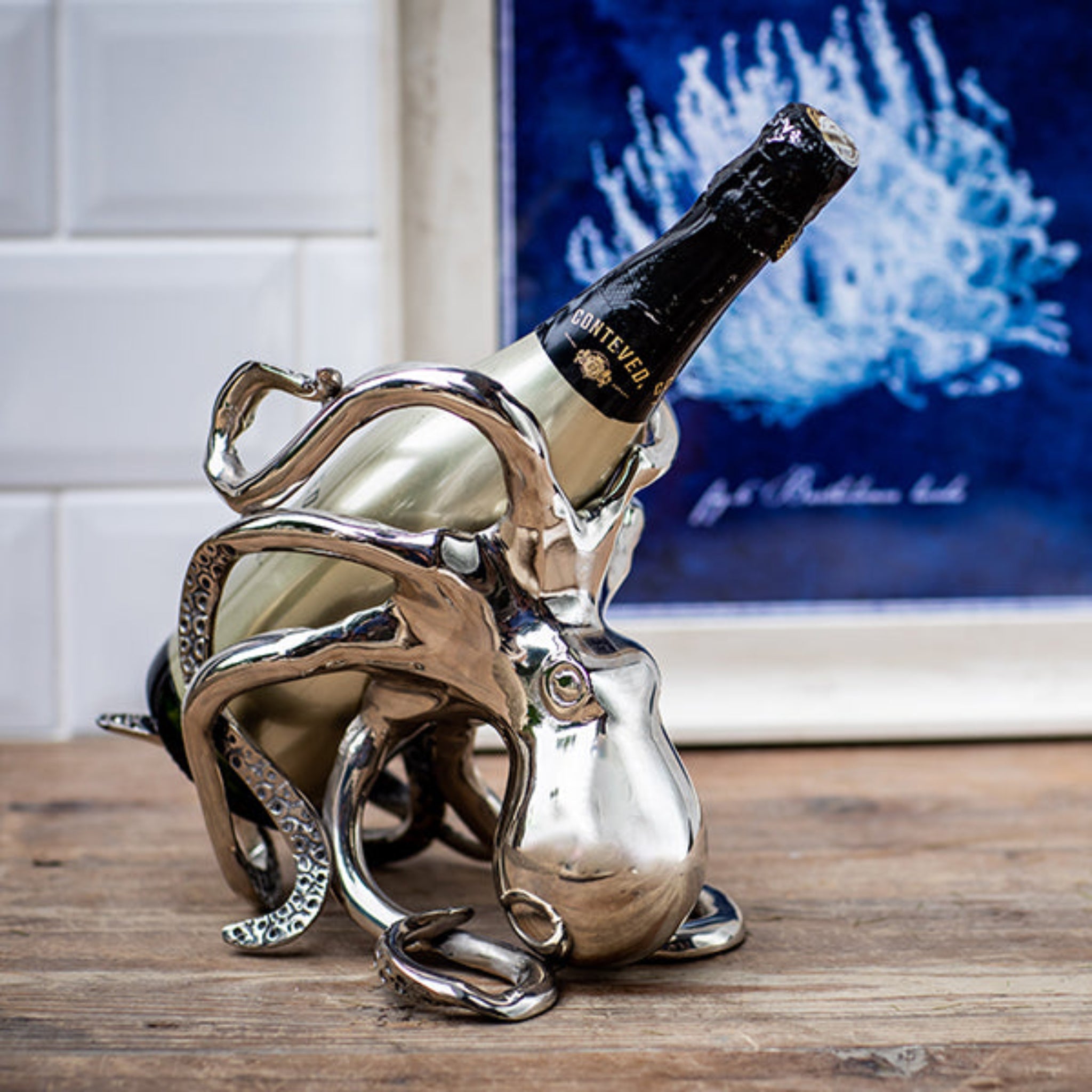Silver octopus-shaped wine bottle holder with a bottle inside on a wooden surface.