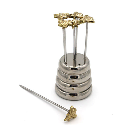 A stainless steel and gold-tone bee-themed pin holder or accessory set on a white background, with a separate long metal pin placed in front.