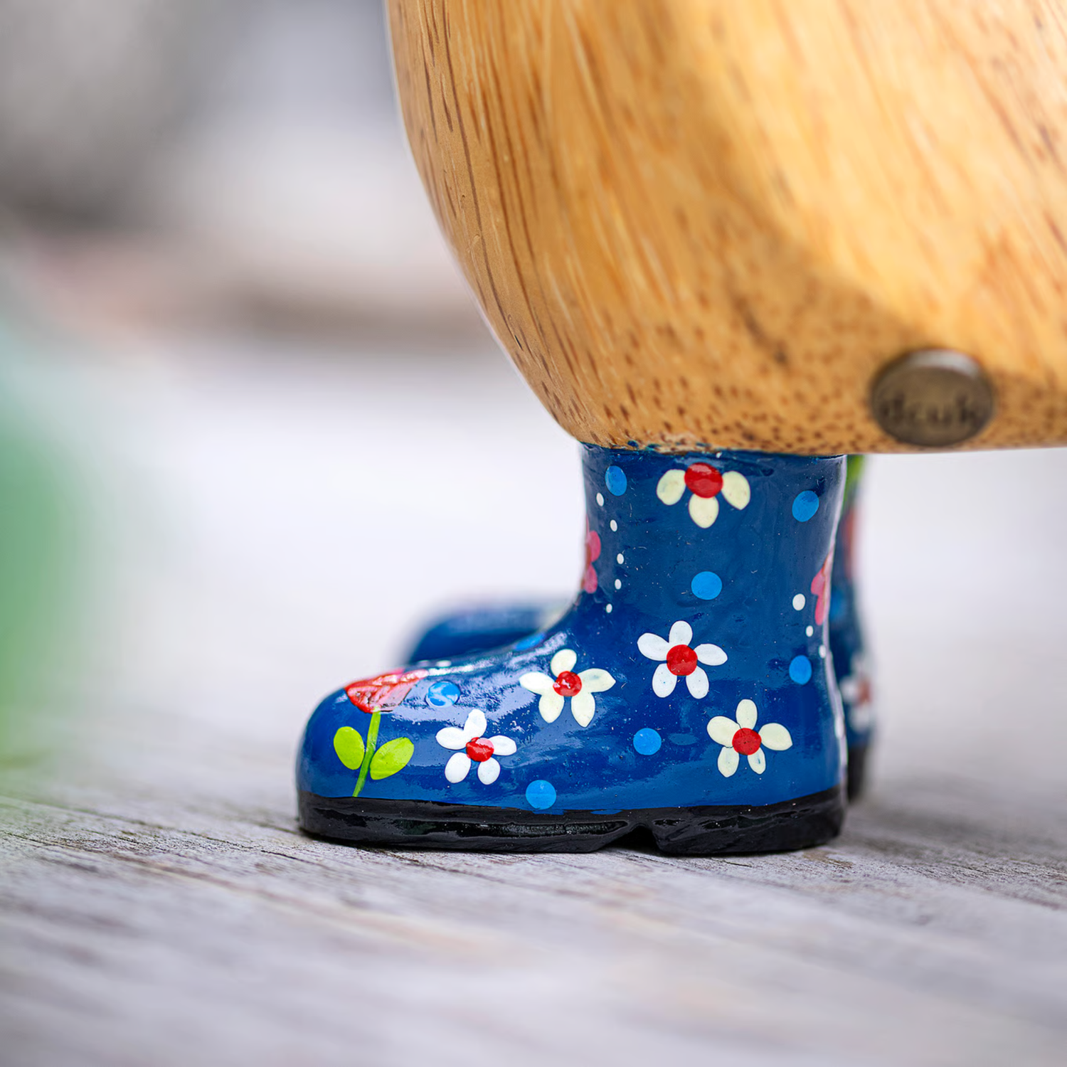 Blue polka dot rain boot with floral patterns on a wooden duck