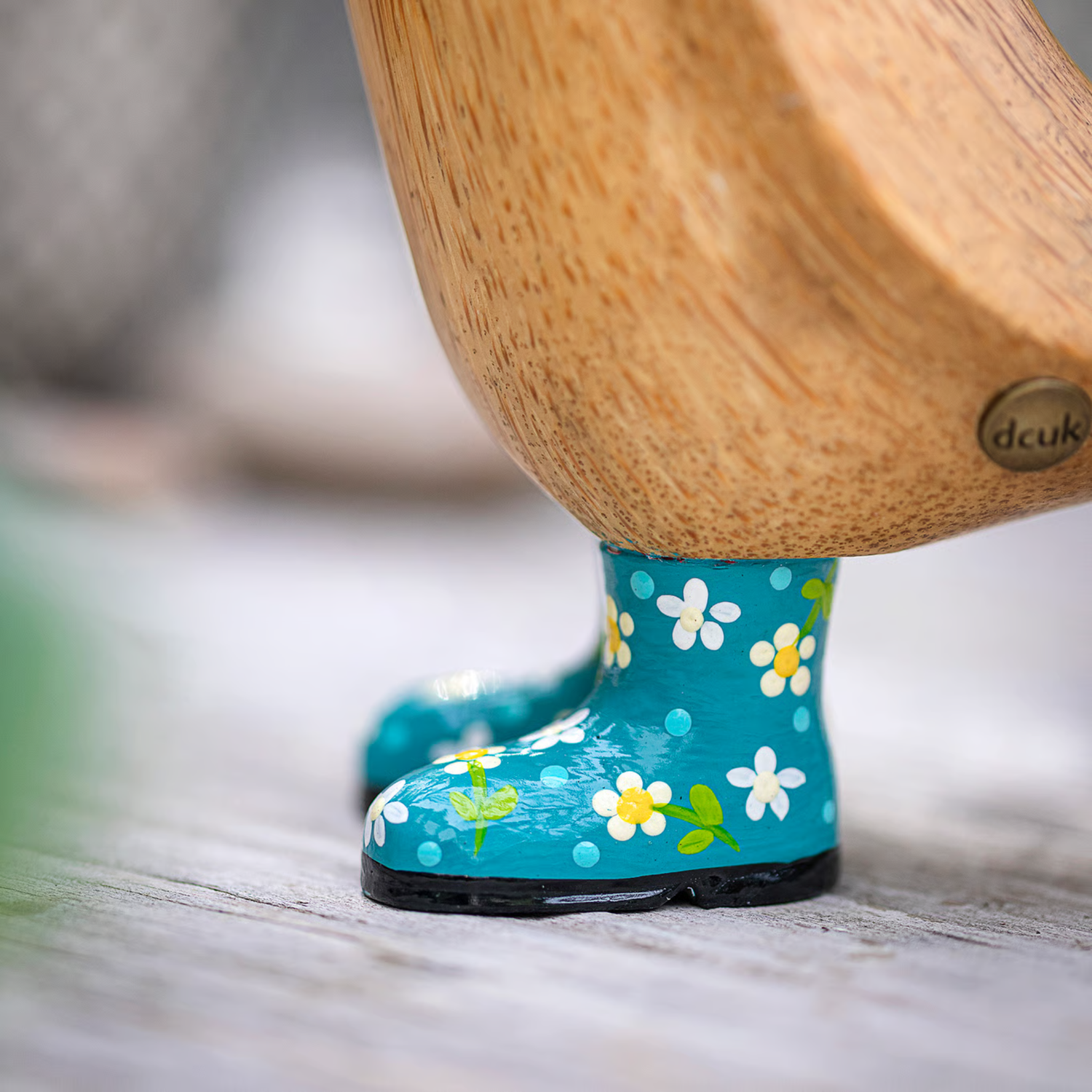Blue floral-patterned rain boots with a wooden duck on a blurred background