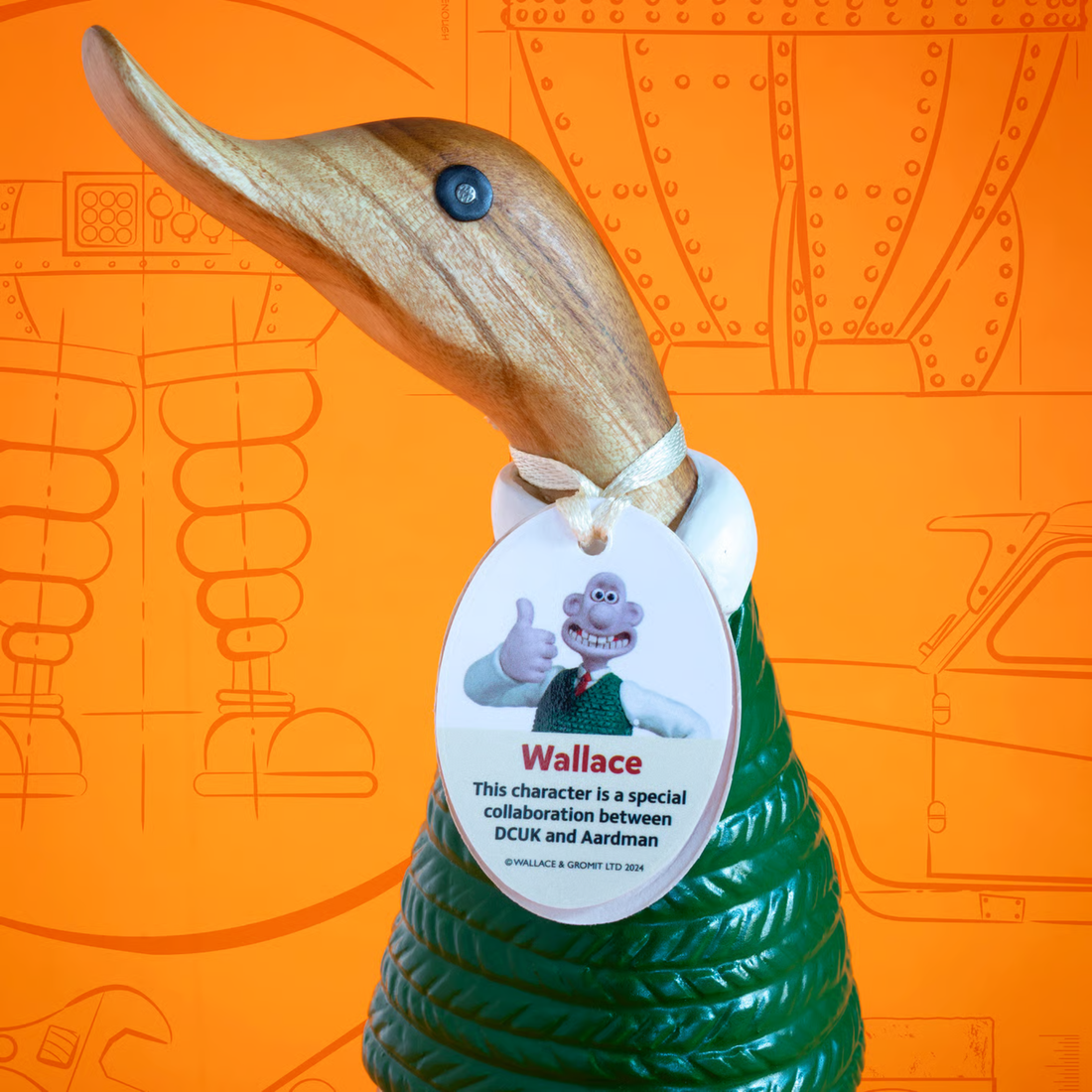 Wooden duck figure with a tag featuring Wallace, a character from DCUK and Aardman, on an orange background.