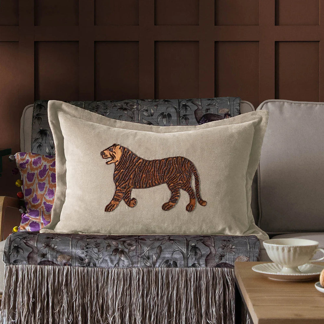 Decorative pillow with a tiger design on a couch against a brown paneled wall.