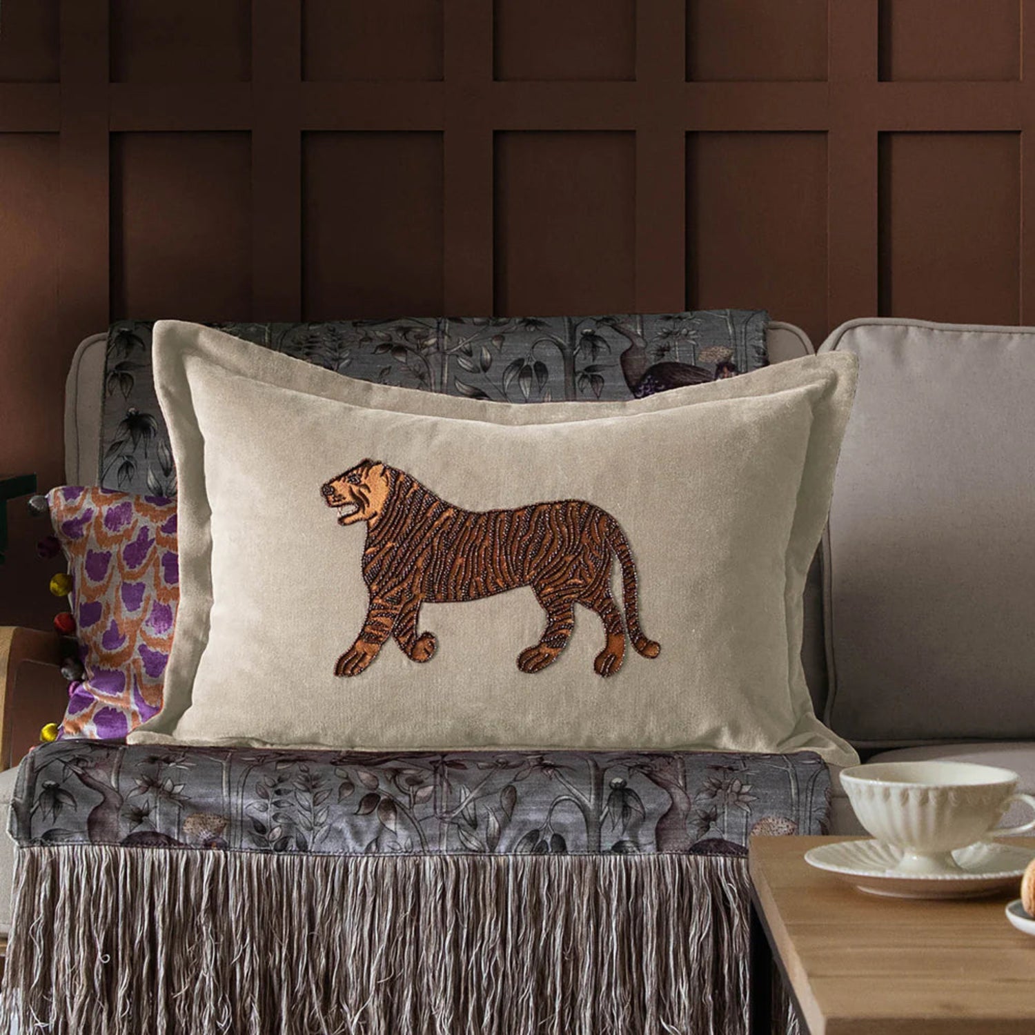 Decorative pillow with a tiger design on a couch against a brown paneled wall.