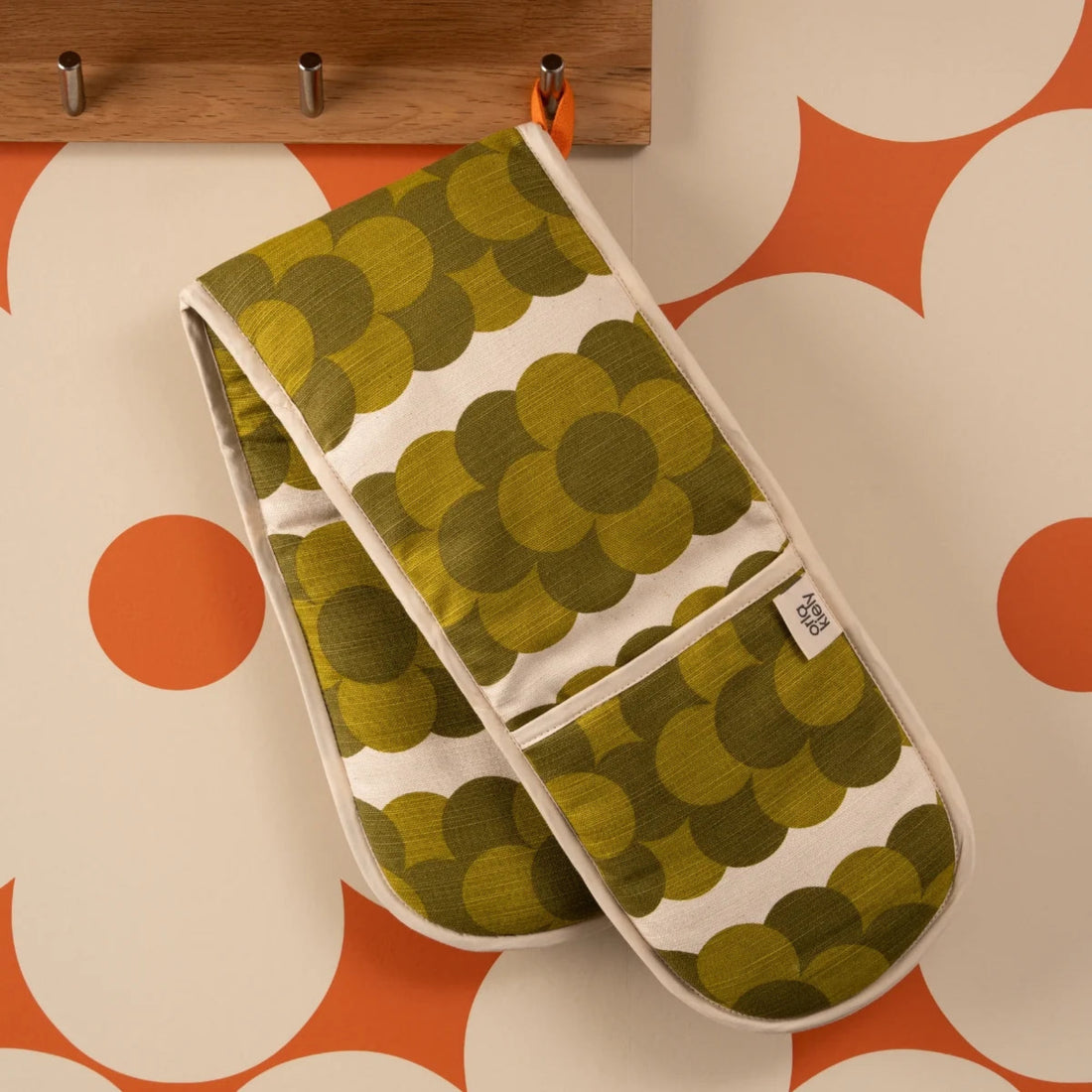Pair of green patterned oven mitts on a surface with orange and white geometric design.