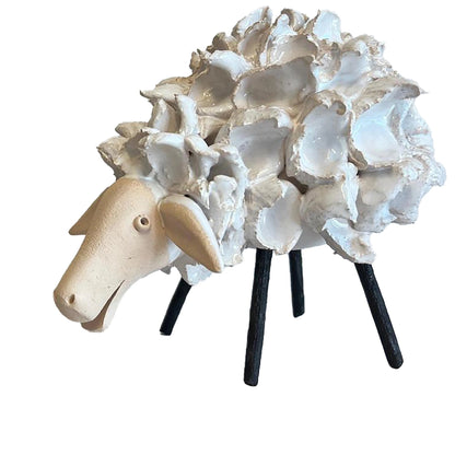 Decorative sheep sculpture with shell-like material on a white background
