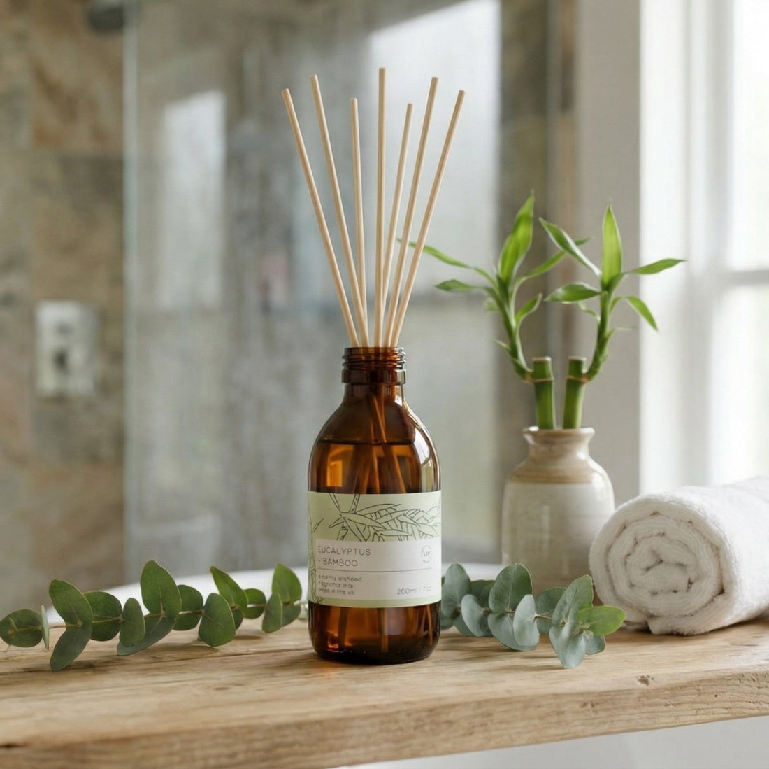 Aromatherapy diffuser on a bathroom counter with towels and plants in the background