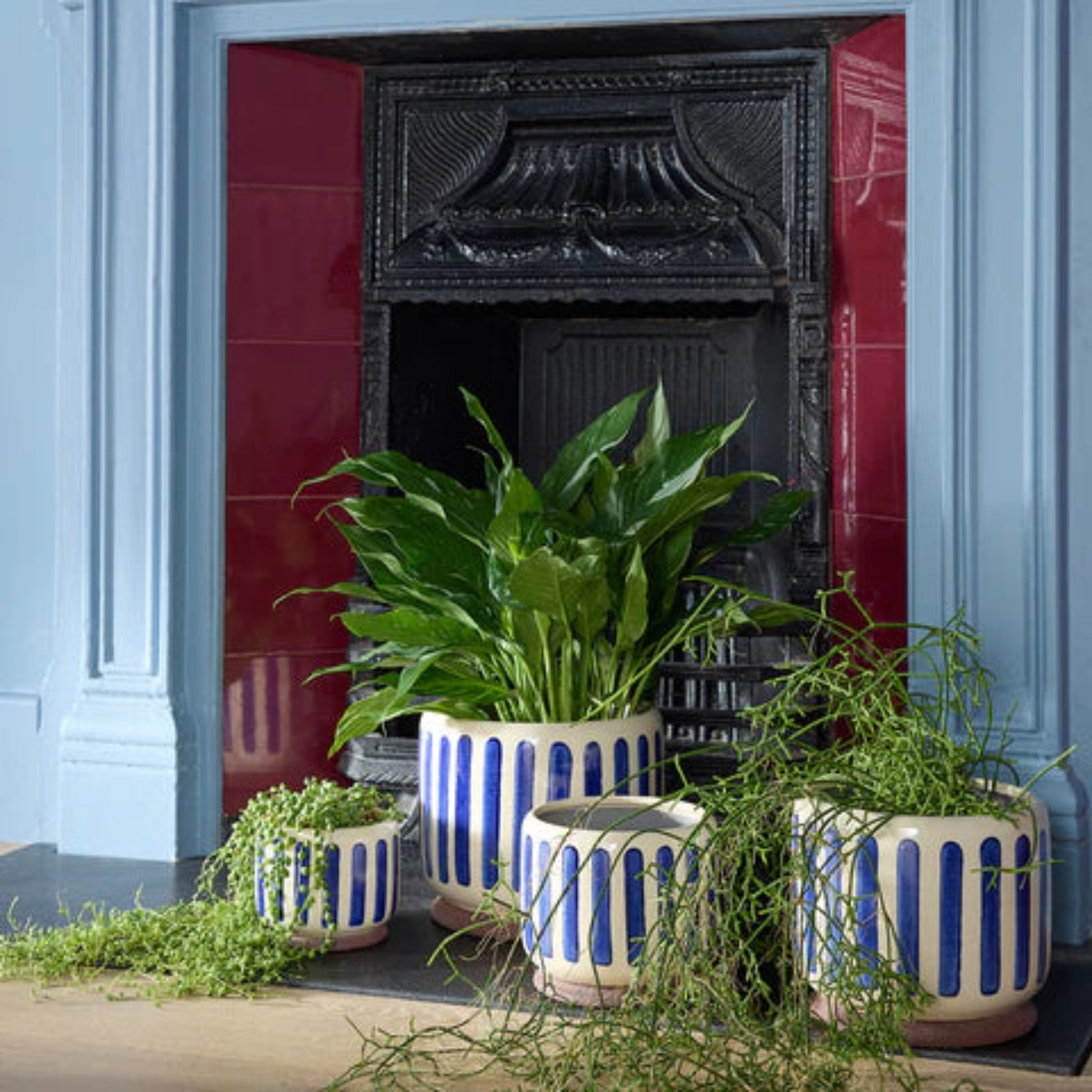 Decorative pots with blue stripes in front of a fireplace.