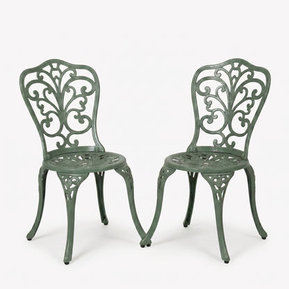 Two green metal chairs with intricate designs on a white background