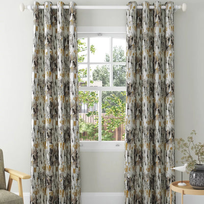 A pair of floor-length taupe grommet curtains hanging on a white rod in a bright, modern room with a window, light wood floor, and a small side table.