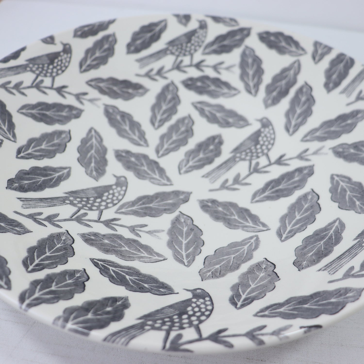 Patterned plate with birds and leaves on a white background
