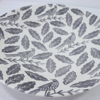 Patterned plate with birds and leaves on a white background