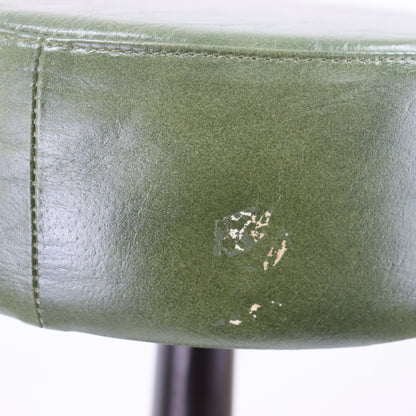 Close-up of a green leather chair with a noticeable scratch on a white background