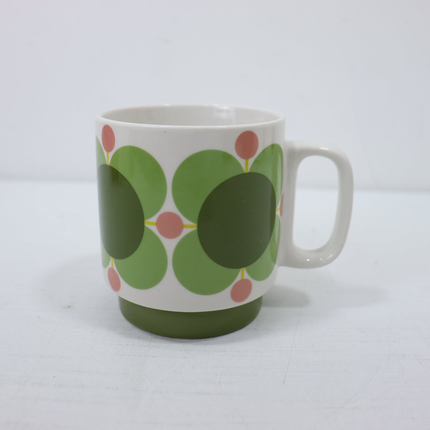 a white mug with green and red circles on it