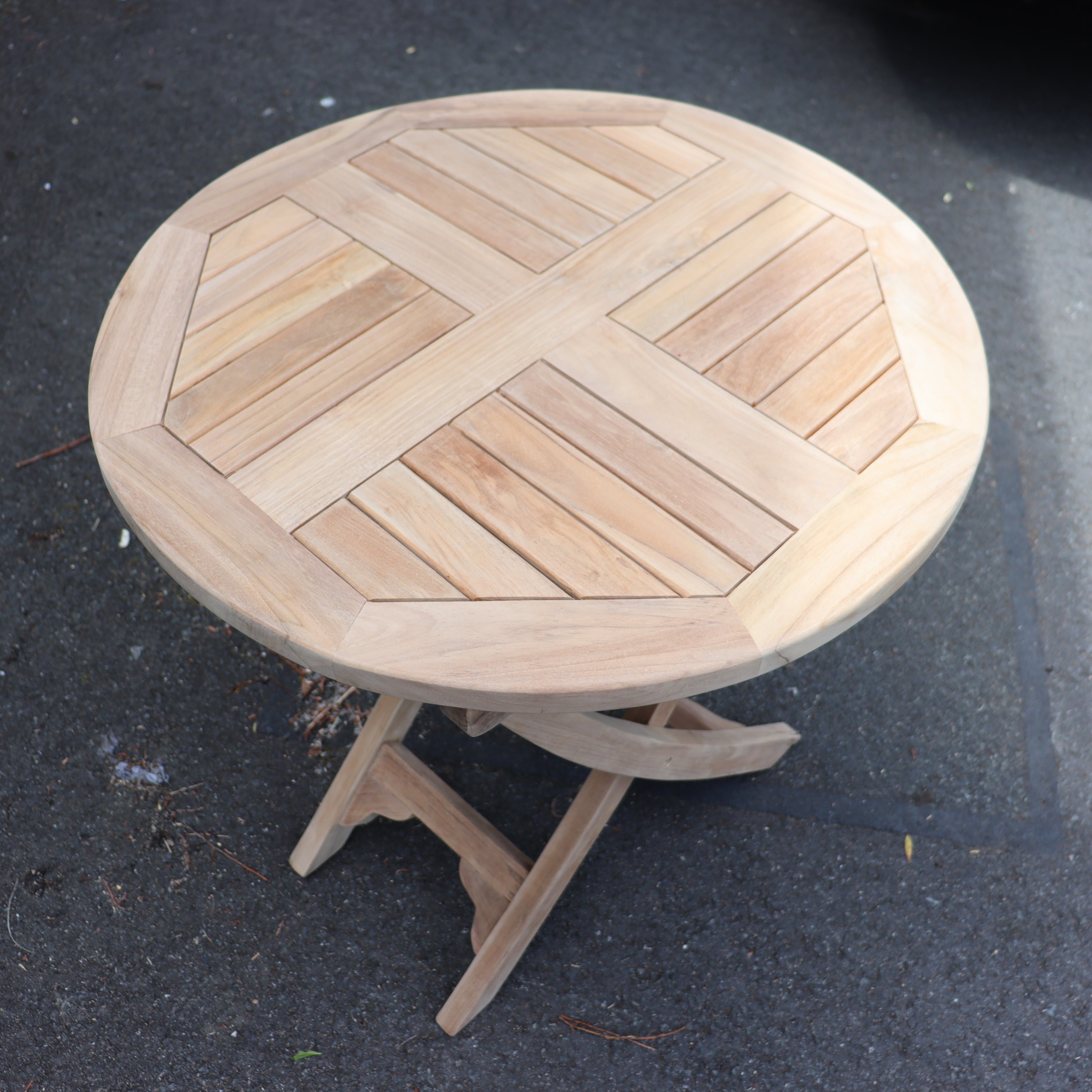 a round wooden table on a sidewalk
