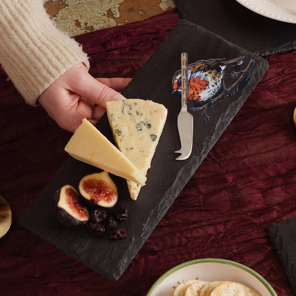 a person holding a piece of cheese on a slate plate