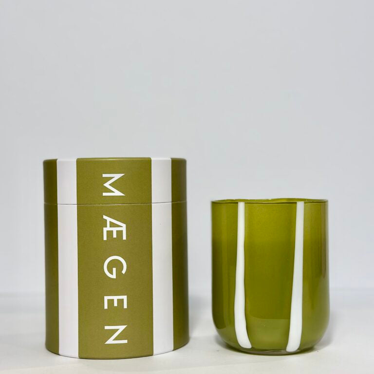 Green candle with white stripes and matching container on a light gray background
