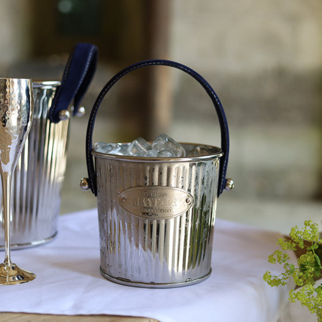 Silver ice bucket with a handle on a table with a blurred background
