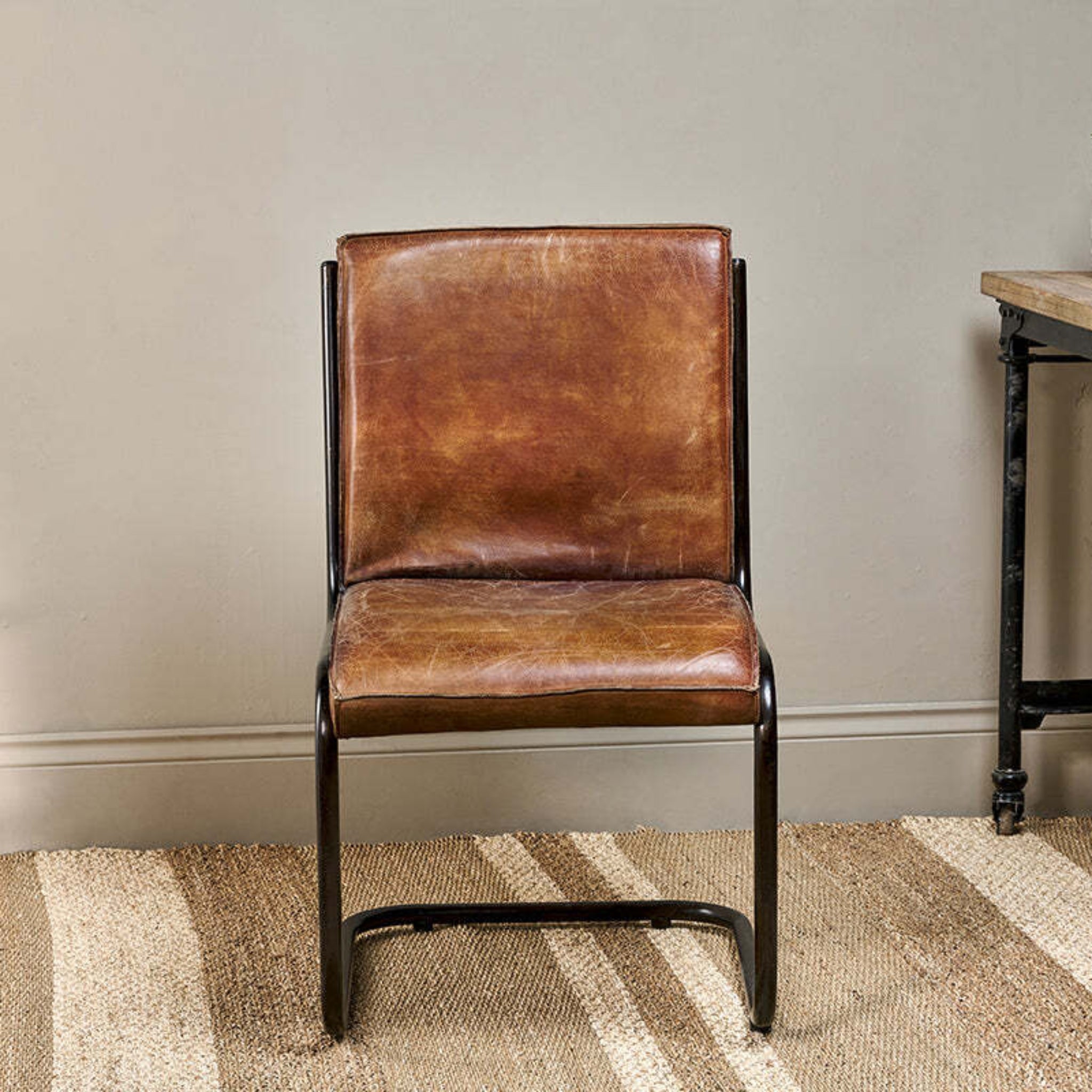 Brown leather chair in a room with a wooden table and plant
