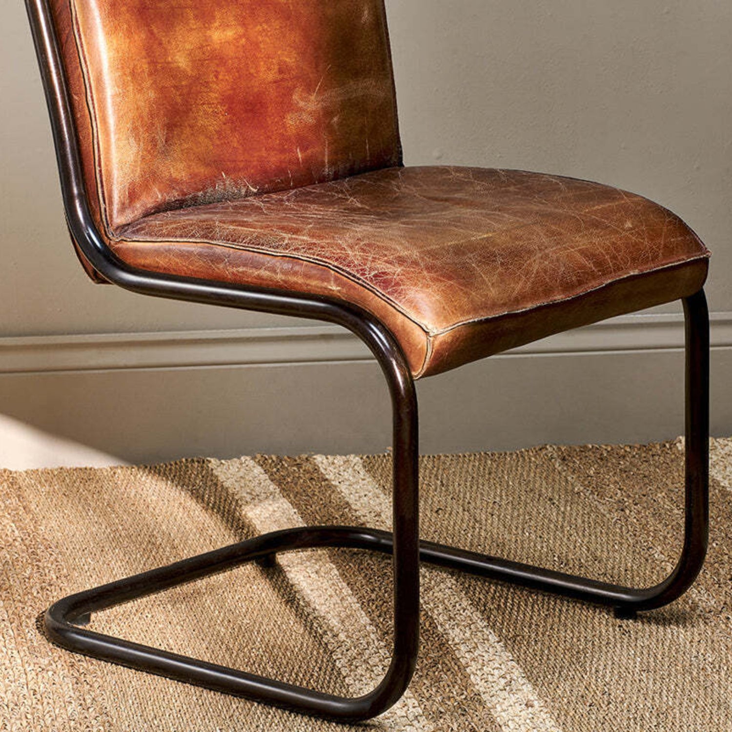 Brown leather chair with metal frame on a striped carpet